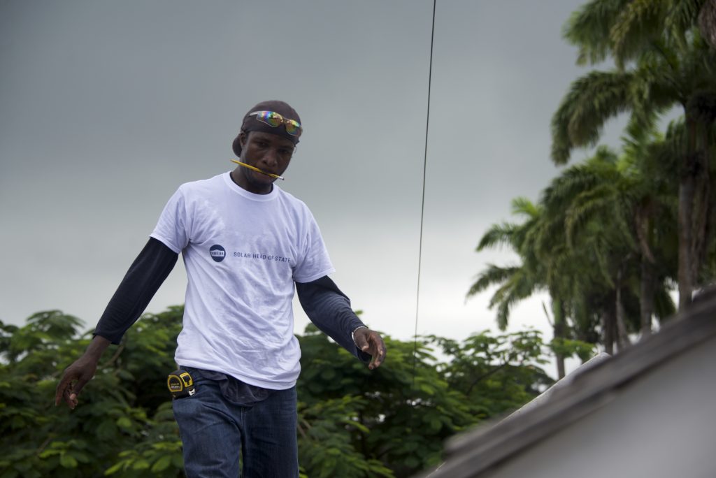 Man on the roof: Rafique Bruno works to beat the rain as panels go onto the roof of Government House, Solar Head of State's premier installation and the residence of St. Lucia's Governor-General.